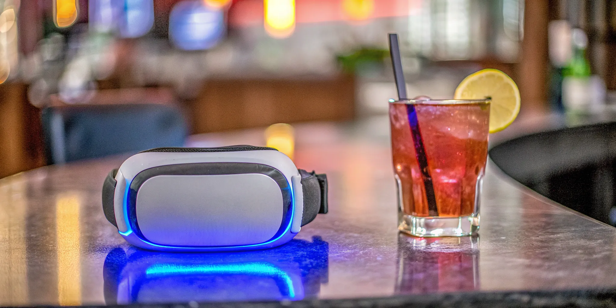 A VR headset and a cocktail resting on the counter of a bar